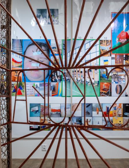 zdjęcie ukazujące fragment wystawy w gsw, brama z napisem szkoła, w tle układ licznych fotografii