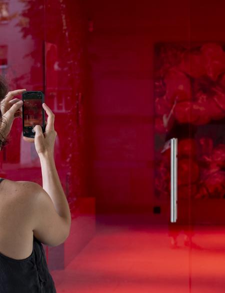 zdjęcie, widok na galerię aneks w Opolu, w tle czerwony obraz, na pierwszym planie oglądająca wystawę