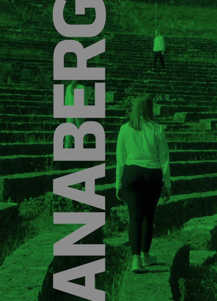 baner informacyjny zawierający napis "anaberg", zielone zdjęcie w tle przedstawia grupę kobiet stojących na widowni amfiteatru